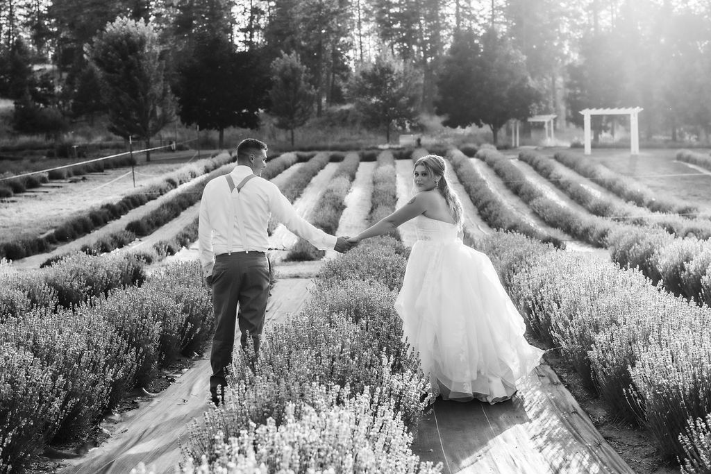 Bride and groom walking through blooming lavender fields at Lavender Manor near Spokane.