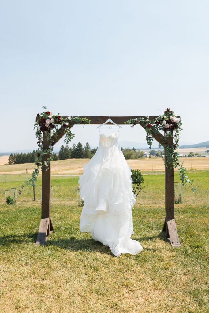 White wedding dress hanging up on an outdoor wedding ceremony with gardens and mountain views