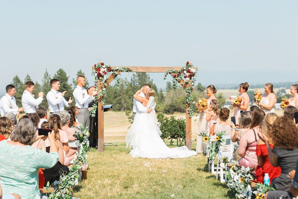 Bride and groom kissing after their wedding vows at a garden wedding venue in Spokane with outdoor wedding ceremony & mountain views