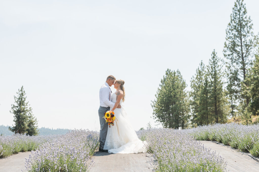 Bride & groom kissing in a field of Lavender as they pose for wedding day photos at a Spokane wedding venue