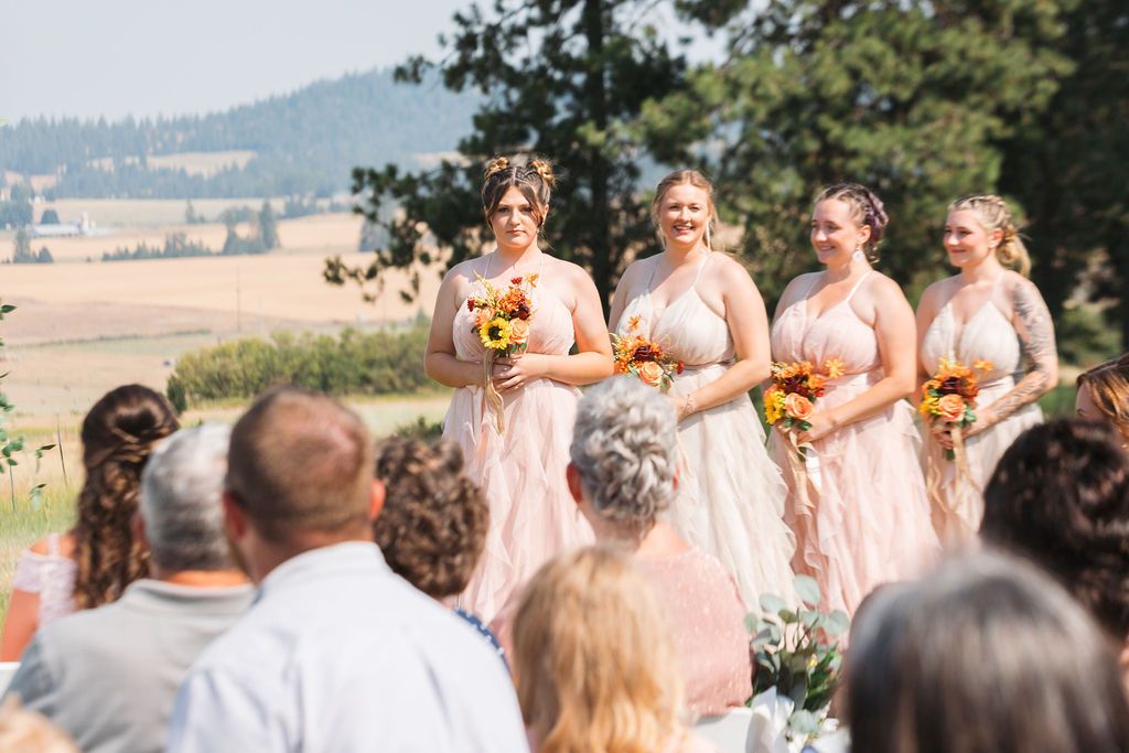 Bridesmaids wearing pink, hold sunflower bouquets as they chat about how A Modern All-Inclusive Wedding Should Include Communication